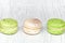 Three macarons on a light wooden table. Close up