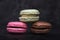 Three macaroons on dark background