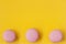 Three macaroons of pink color on yellow background, top view. Romantic morning, gift for beloved. Breakfast on Easter