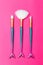 Three makeup brushes mermaid tail on a bright pink background. Vertical