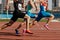 three male athletes sprinting on red track