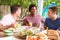 Three Male Friends Enjoying Meal Outdoors At Home