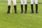 three male horse polo players in white trousers and special boots for riding a horse. People stand on a green lawn. In