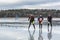 Three male ice skaters on wet watery and frozen lake.