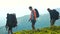 Three male tourists with backpacks hike on mountain.