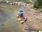 Three Man Filling Water Into Jerry Can in the River