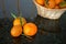 Three mandarin oranges in front of wicker basket on black granite
