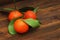 Three Mandarins with Green Leaves on a Rustic Wooden Table. Isolated. view from Above.