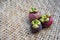 Three mangosteens on a woven bamboo basket