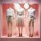 Three mannequins in a display case with white shirts and skirts, AI