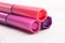 Three markers or pens in pink, purple, pink on a white concrete background, slide or pile