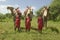 Three Masai Warriors in traditional red toga pose with their camels at Lewa Wildlife Conservancy in North Kenya, Africa