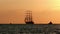 Three-masted full-rigged tall ship in close to coast at sunrise one summer morning. silhouette tourist vessel floats in Harbor