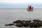 Three-Masted Sailboat Along a Rocky Shore