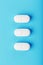 Three medicinal tablets in a row on a blue background, isolate