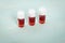 Three medicine vials filled with red liquid on green background