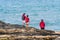 Three members of the same family, father, mother and eldest son dressed in the same red jacket, from the top of a cliff