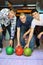 Three men bent over to heave up balls for bowling