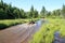 Three men driving ATV quad through dirty water in forest