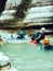 Three men in helmets and wetsuits are rafting down the river flowing between the canyons. Extreme vacation. Canyoning