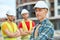 Three men in protective helmets standing on the building site