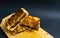 three messy stack of chocolate filled toasted bread on wooden cutting board with black background