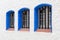 Three metal grilled windows with blue frames in mediterranean Sitges