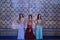 Three middle-aged Hispanic women in beautifully colored and beaded dresses for belly dancing, posing with a wall of beautiful