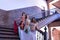 Three middle-aged Hispanic women in beautifully colored dresses with rhinestones to belly dance, posing on stairs next to a wooden