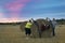 three middle-aged women friends joke and laugh in a field with haystacks