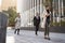 Three millennial city workers walking in the street, low angle, full length