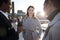 Three millennial colleagues stand talking on Millennium Bridge as the sun goes down, close up