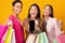 Three Millennial Girls Showing Blank Smartphone Screen, Yellow Background, Mockup