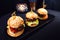 Three mini burgers on a black rectangular elongated stand.