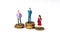 Three miniature people standing on coins