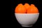 Three minneola oranges in white bowl