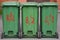 Three mobile green plastic dumpsters with red lettering