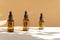 Three mock-ups of unmarked glass bottles, amber in color with dropper lid on beige background with floral shadow. Face