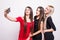 Three models in dresses make selfie.
