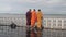 Three monks wearing red, orange and yellow robes on the ferry boat