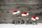 Three mooses wearing santa hats on grey wooden bac