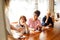 Three motivated elderly women sitting at wooden desk, making notes in notepad, listening to lecturer speaker in office.