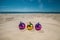 Three multi-colored, bright Christmas balls lie on the sand by the ocean, the sea.