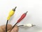 Three multicolored wires in a male hand on a white background