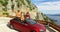 Three multiethnic friends dancing in convertible parked with sea in background