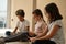 Three multiethnic little kids sit indoor using digital gadgets