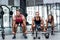 Three muscular athletes lifting a barbell