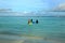 Three muslim women in colorful clothes are standing in water and going swimming. Turquoise water of Indian Ocean, Maldives.