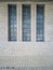 Three narrow windows on the wall of an old building lined with ceramic tiles