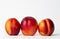 Three nectarines on a white background in a row